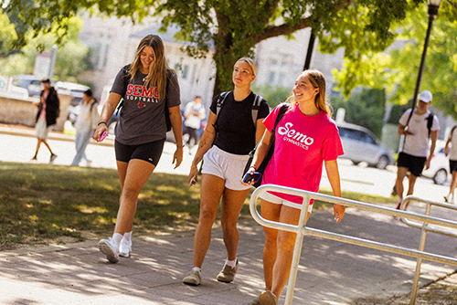 Three students walking around campus, with two wearing SEMO shirts but for different departments.
