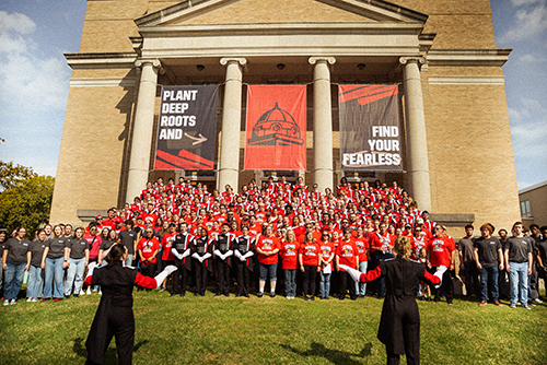 The marching band gathers in front of Wehking Alumni Center for a portrait.