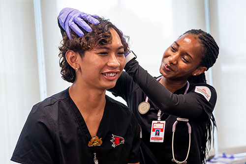 a nursing student in the simulation lab checks the flow of an iv bag