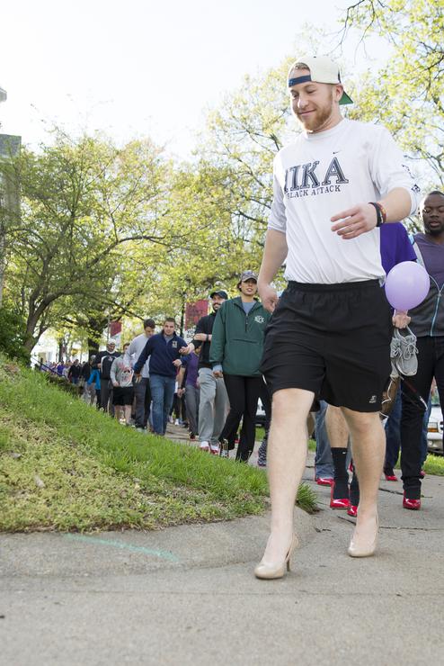 Male students walk in high heels at sexual assault awareness event.
