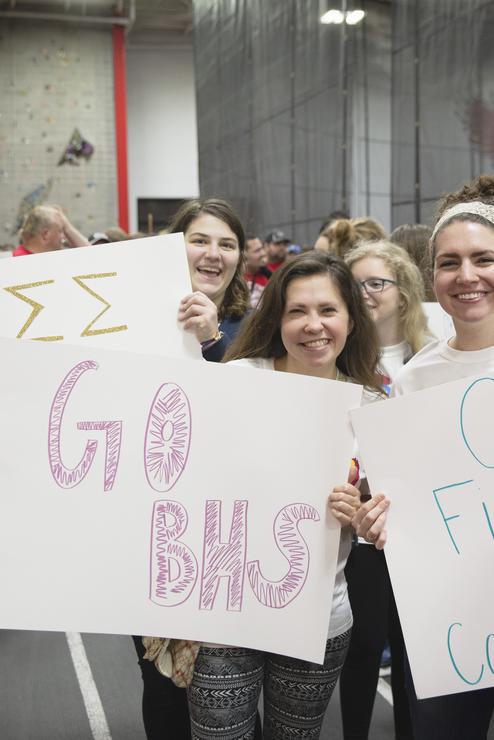 Students smiling and holding signs at Special Olympics.