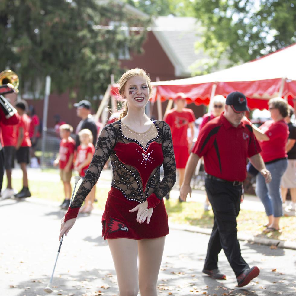 A feature twirler for the Southeast Marching Band smiles walking down the street in front of the band.